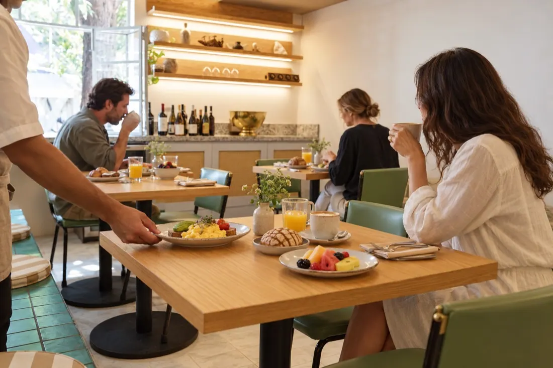 Calma a la hora del desayuno, con huéspedes y un mesero