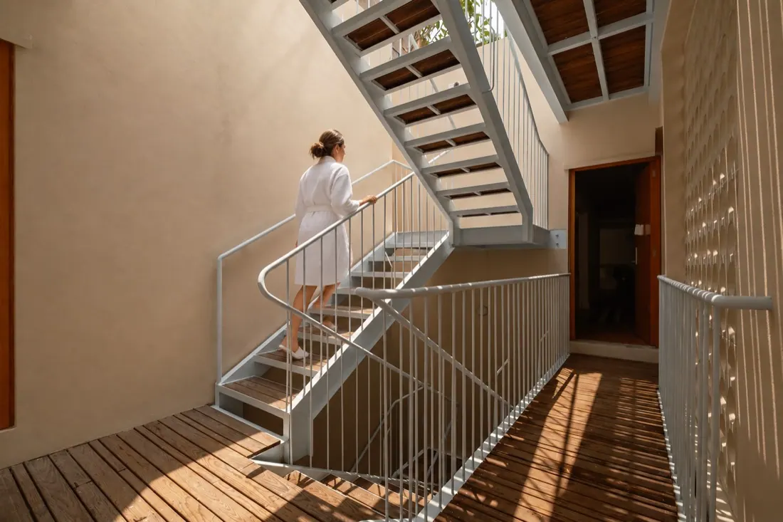 Un huésped en bata subiendo la escalera de acero